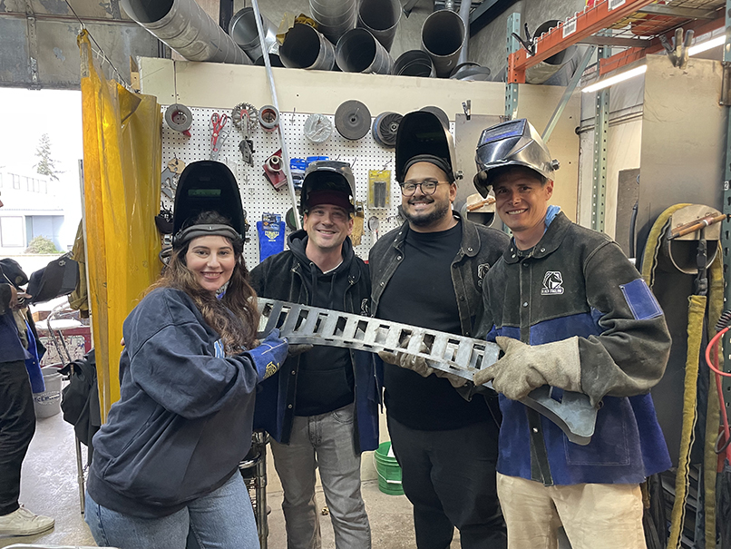 teammates learning to weld during a metalworking workshop